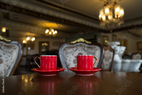 Close up of women's hands holding a red cup of coffee in the cafe concept.