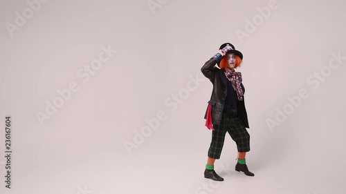 an actor in a hatter costume, he jumps and smiles. At white studio