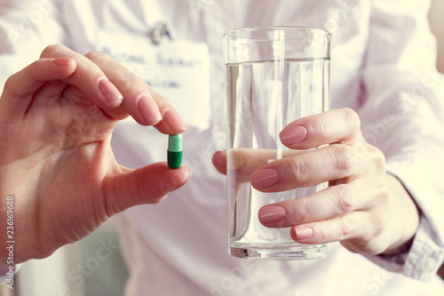 pill and a glass of water in the hands of a doctor