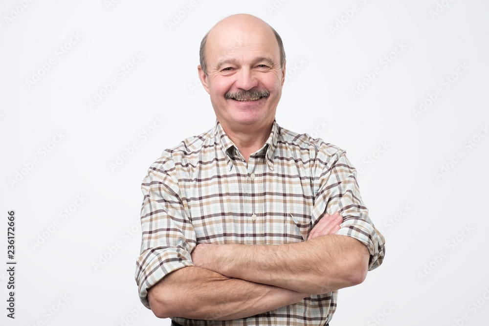Portrait of confident hispanic mature man in shirt looking at camera and smiling while keeping arms crossed. Portrait of confident hispanic mature man in shirt looking at camera and smiling while keeping arms crossed.