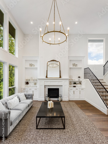 Beautiful Living Room in New Luxury Home with Fireplace. Large Bank of Windows Shows Exterior View of Trees. Vertical Orientation photo