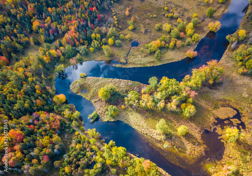 Low level aerial photograph featuring fall foliage in the Adirondack Park of New York State featuring peak fall foliage colors near Saranac Lake, NY and the Saranac River.