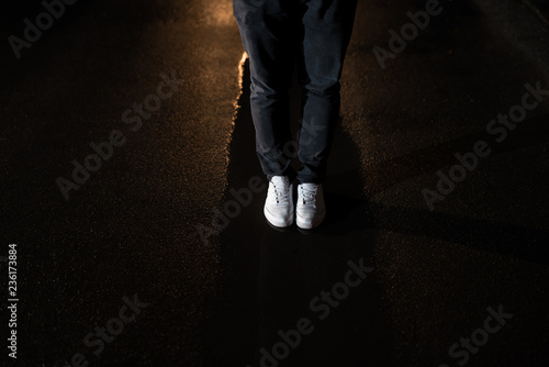 Man legs in water on asphalt in night.