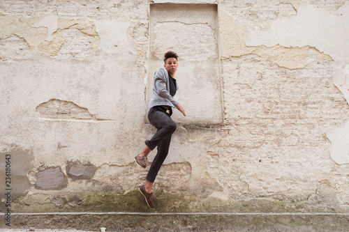 The young man jumping outdoor near the old house wall