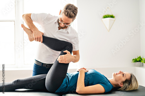 A Modern rehabilitation physiotherapy man at work with woman client working on leg