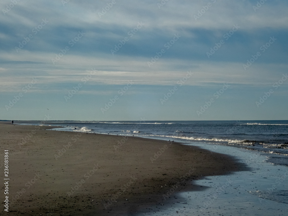 Obraz premium A lonely walker on the beaches of the Ameland island in the Netherlands in Autumn