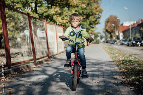 Fototapeta Naklejka Na Ścianę i Meble -  Little boy on a bicycle ride on a pavement in a town