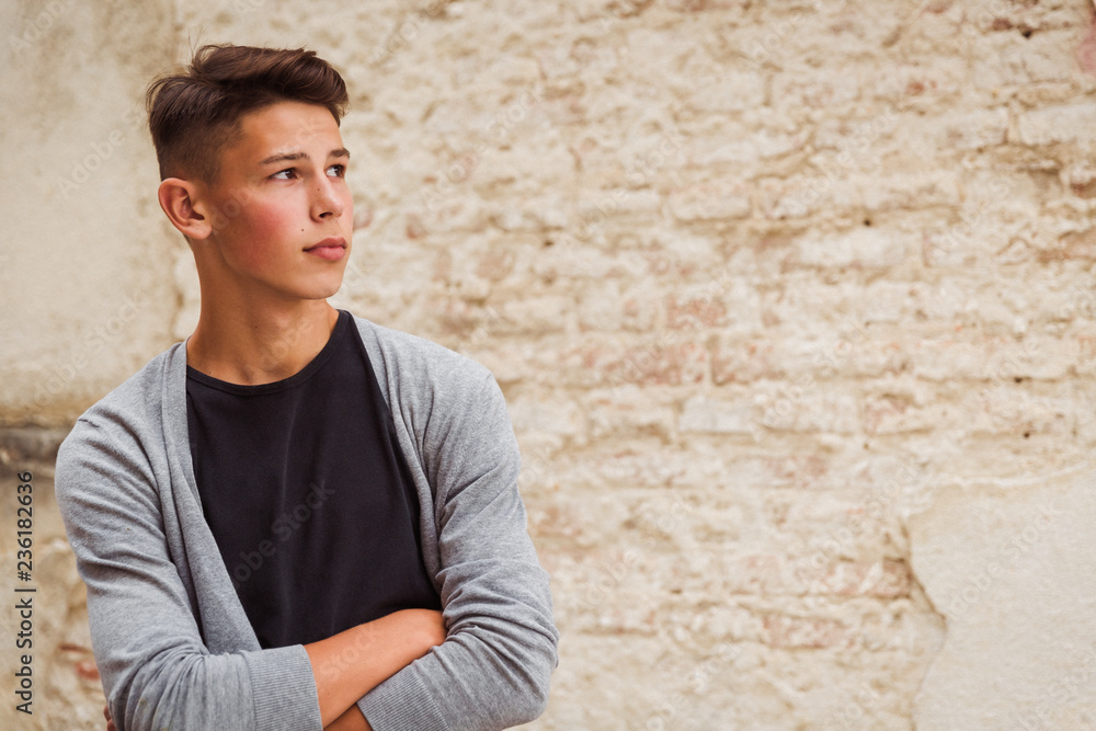 Portrait of the young man who is standing outdoor near the old house wall and looking aside Portrait of the young man who is standing outdoor near the old house wall and looking aside