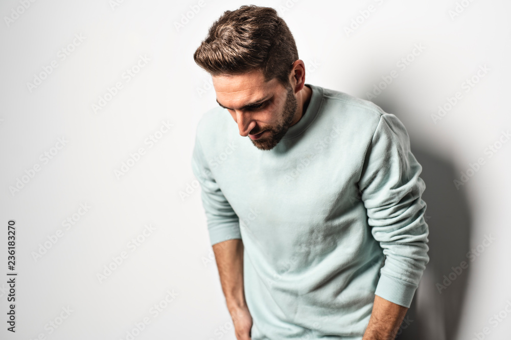 A young man looking away while standing on gray background A young man looking away while standing on gray background
