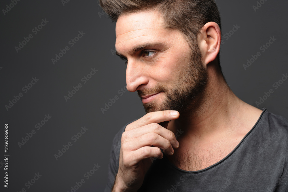 young man looking away while standing on dark background young man looking away while standing on dark background