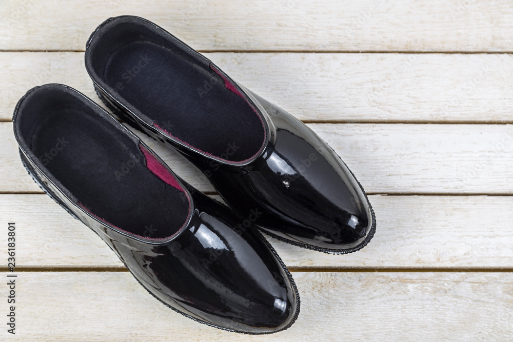 Black rubber galoshes on a white wooden table Black rubber galoshes on a white wooden table