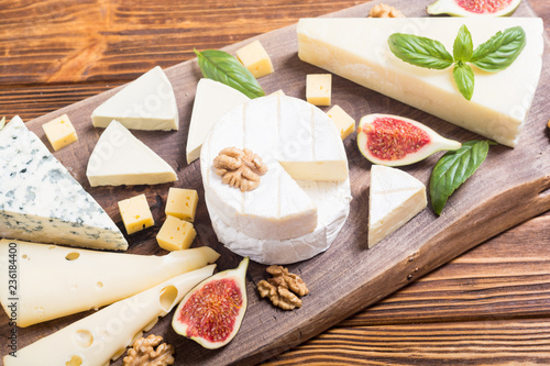 Cheeseboard with cheese brie , parmesan , camembert and dorblu . Food on wooden board