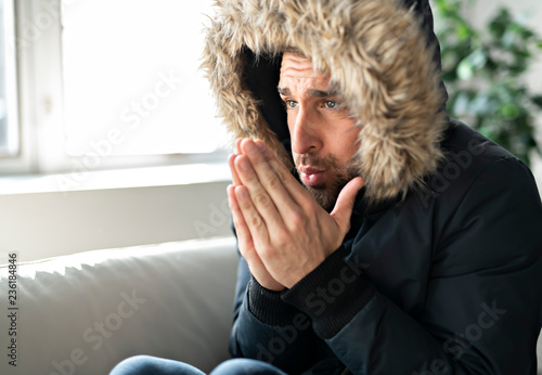Fotografia A Man have cold on the sofa at home with winter coat