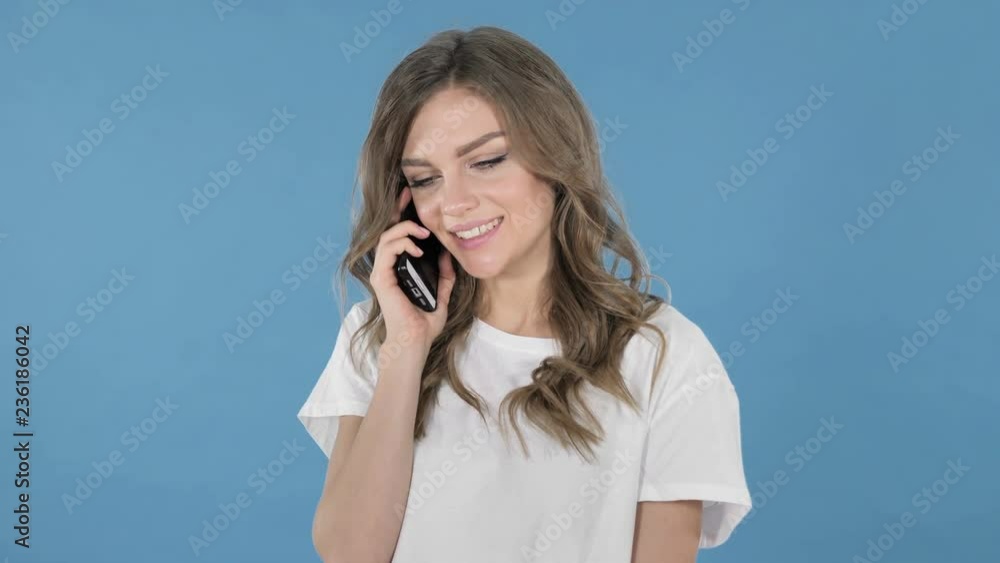 Young Girl Talking on Smartphone Isolated on Blue Background Young Girl Talking on Smartphone Isolated on Blue Background