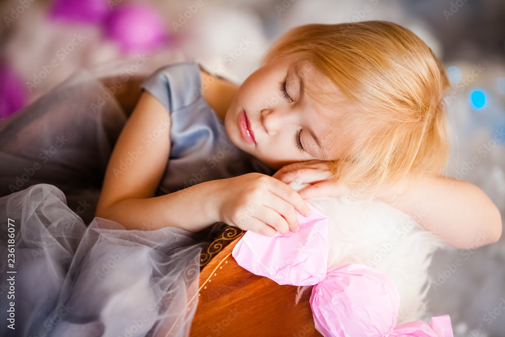 Nice little blonde sleeping girl siting in the toy sledge with white fur. Christmas and New Year theme Nice little blonde sleeping girl siting in the toy sledge with white fur. Christmas and New Year theme
