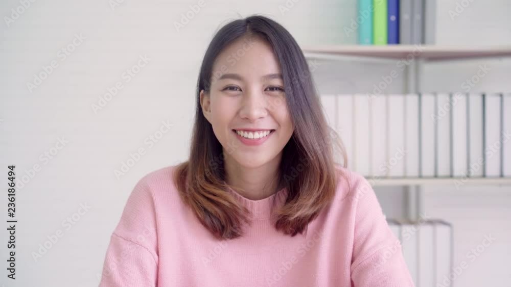 Teenager Asian woman feeling happy smiling and looking to camera while relax in her living room at home. Beautiful Asian young female using relax time at home concept. Teenager Asian woman feeling happy smiling and looking to camera while relax in her living room at home. Beautiful Asian young female using relax time at home concept.