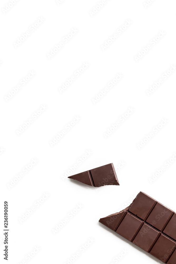 Broken dark chocolate bar isolated on white table. Vertical composition. Top view Broken dark chocolate bar isolated on white table. Vertical composition. Top view