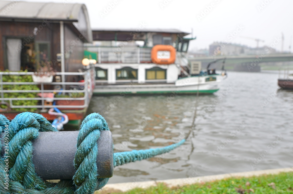 Close up of a blue mooring rope tied around a fixing on the quayside and holding boats