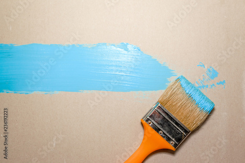 paint brush in blue paint on an unpainted flat surface, copyspace