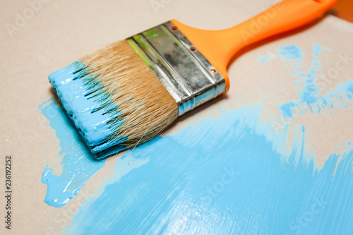 paint brush in blue paint on an unpainted flat surface