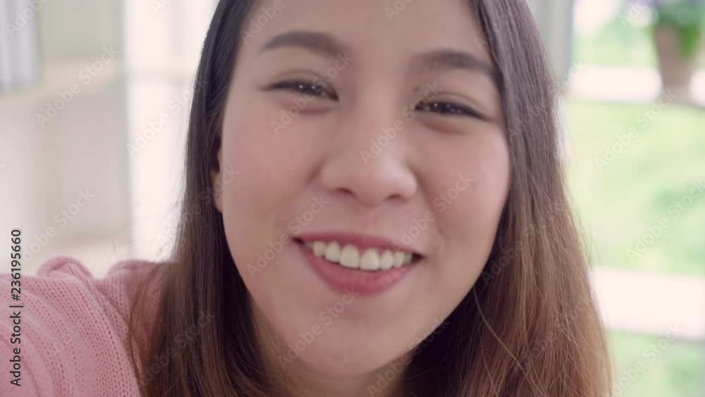 Asian blogger woman using smartphone recording vlog video in living room at home,female enjoy funny moment while lying on the sofa when relax at home. Lifestyle blogger making video at home. Asian blogger woman using smartphone recording vlog video in living room at home,female enjoy funny moment while lying on the sofa when relax at home. Lifestyle blogger making video at home.