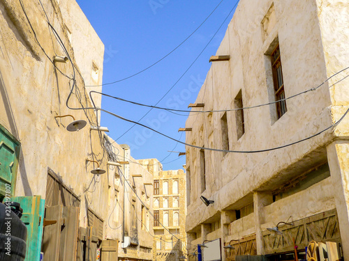 White buildings line a narrow alleyway in the labyrinthine historical district of Souq Waqif   Standing Market    the oldest marketplace in Qatar  in Doha s old town