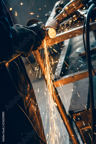 Close up of car mechanic hands welding grinding machine.Sparks of grinding machine while cutting car exhaust pipe