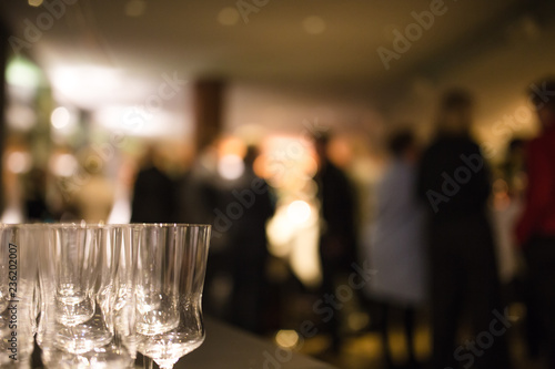 Champagne glasses at a dinner party, with party guests in background