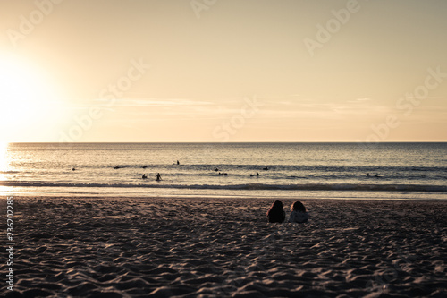 Ladies lie on surf beach at sunset, Praia da Foz, Portugal