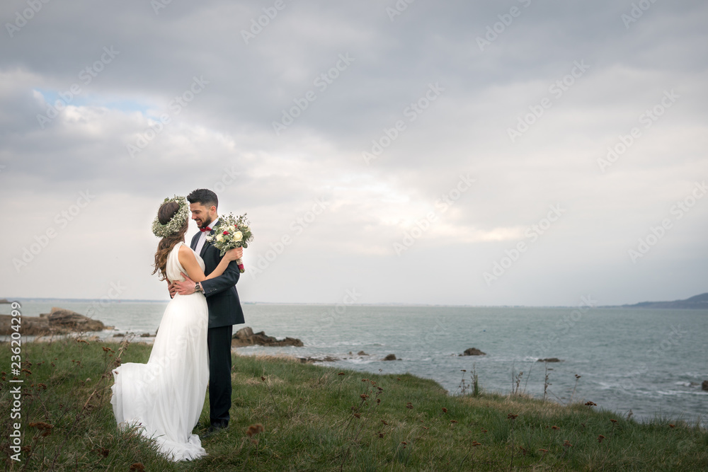 young couple bride groom getting married wedding posed photos at seaside sea beach hairpiece flowers bouquet church