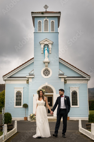 Obraz na płótnie young couple bride groom getting married wedding posed photos at seaside sea beach hairpiece flowers bouquet church w salonie