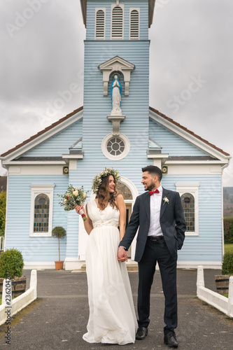 Obraz na płótnie young couple bride groom getting married wedding posed photos at seaside sea beach hairpiece flowers bouquet church w salonie