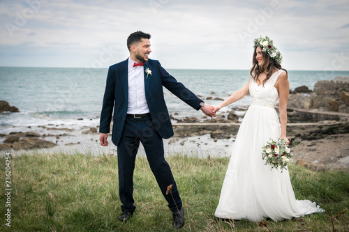 young couple bride groom getting married wedding posed photos at seaside sea beach hairpiece flowers bouquet church
