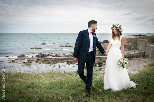Obraz na płótnie young couple bride groom getting married wedding posed photos at seaside sea beach hairpiece flowers bouquet church w salonie