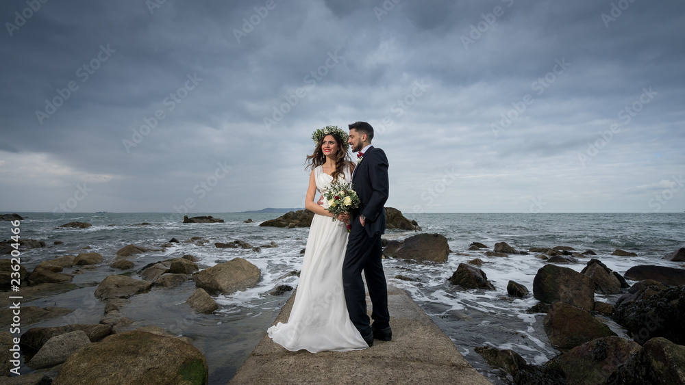 young couple bride groom getting married wedding posed photos at seaside sea beach hairpiece flowers bouquet church