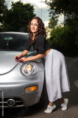 Closeup portrait happy, smiling, attractive woman, near her car on the city street. Personal transportation, auto purchase concept