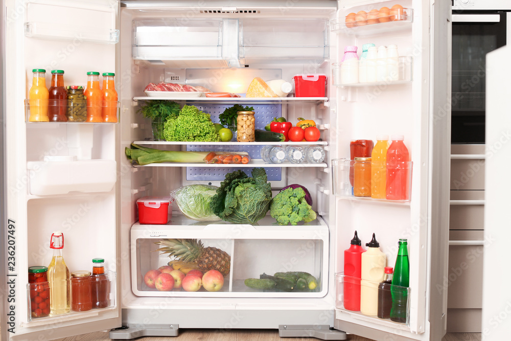 Open refrigerator filled with different food in kitchen Open refrigerator filled with different food in kitchen