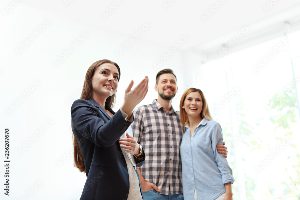 Female real estate agent showing new house to couple, indoors Female real estate agent showing new house to couple, indoors