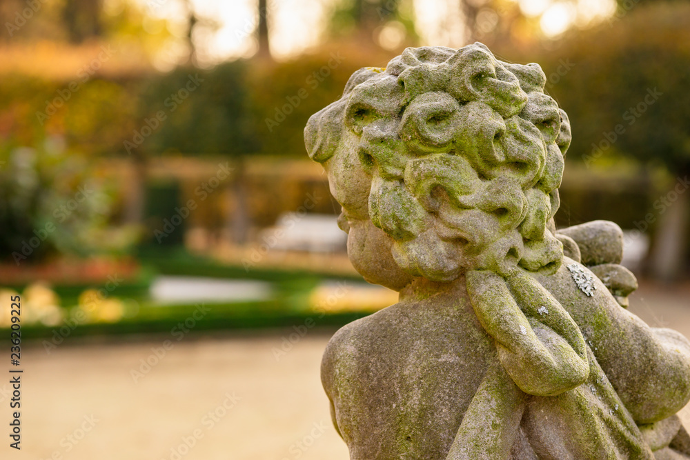 Stone angel statue in garden. Guardian angel statue in sunlight as a symbol of love in garden. Stone angel statue in garden. Guardian angel statue in sunlight as a symbol of love in garden.