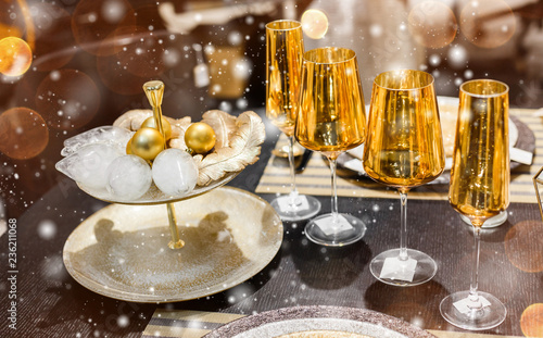 Christmas table place setting with gold christmas decorations, bokeh, snowflakes. Xmas and Happy New Year theme, selective focus