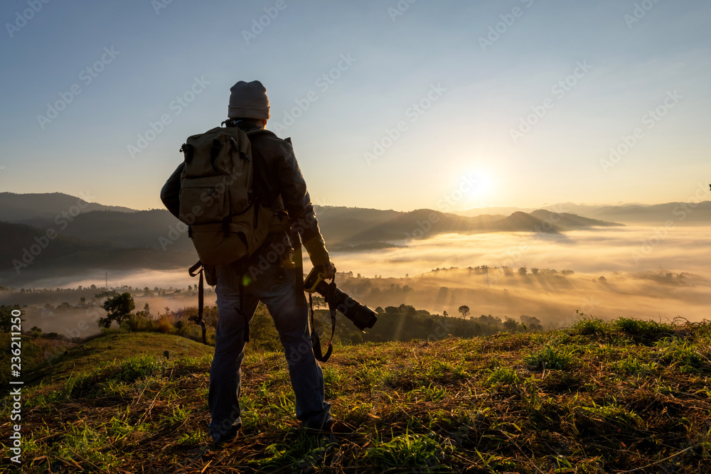 Photographer take photos with mirror camera on peak of mountain. misty landscape, spring orange pink misty sunrise in beautiful valley below. Photographer take photos with mirror camera on peak of mountain. misty landscape, spring orange pink misty sunrise in beautiful valley below.