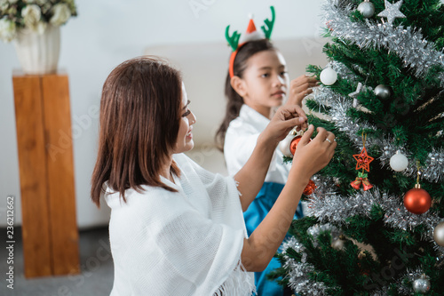 mom and daughter decorating christmas tree photo