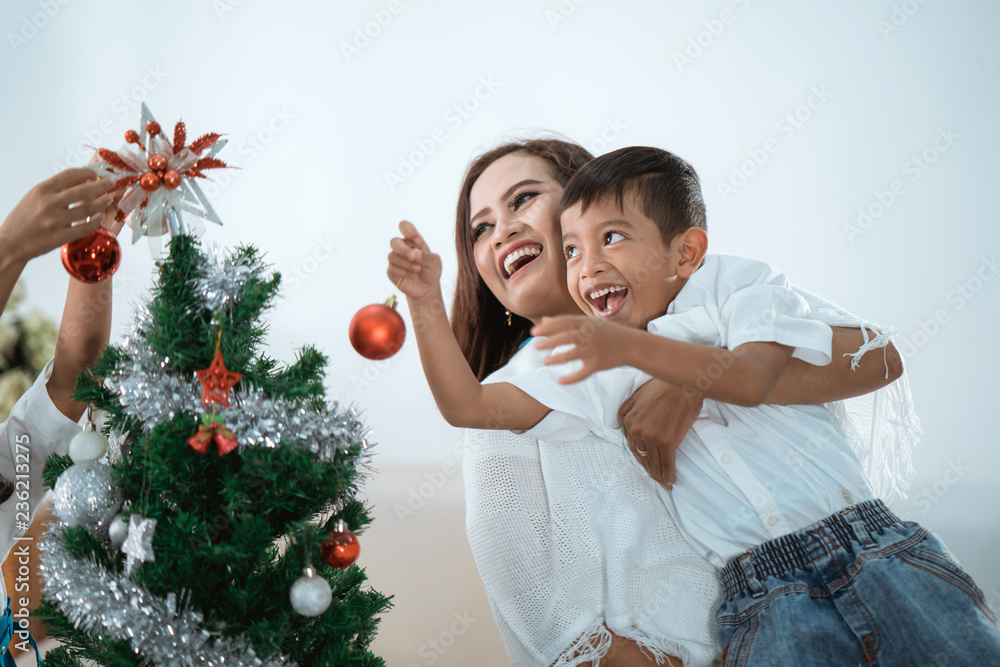 mother and son decorating christmas tree mother and son decorating christmas tree