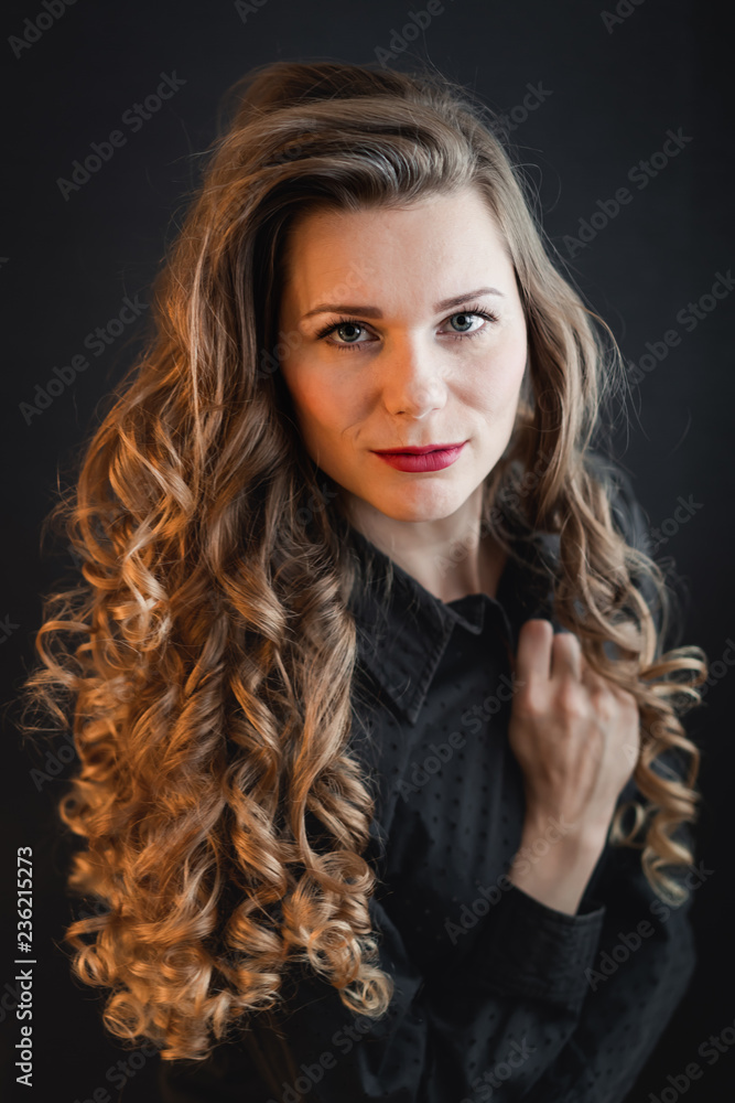 Fototapeta premium Portrait of a young woman with curly hair in a black shirt