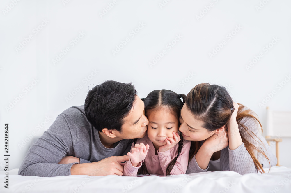 Portrait happy Asian family kissing daugther over white background Portrait happy Asian family kissing daugther over white background