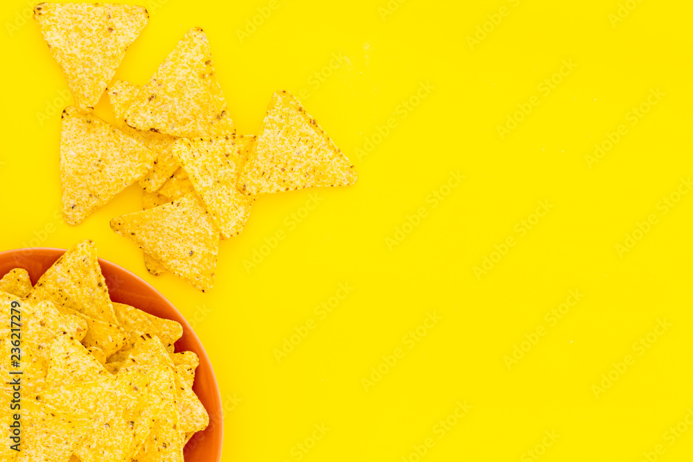 Mexican snack. Make nachos. Crispy nachos on plate on yellow background top view copy space Mexican snack. Make nachos. Crispy nachos on plate on yellow background top view copy space