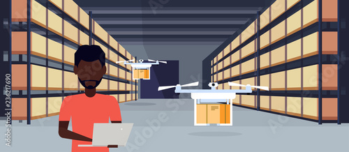 african man operator drone flying working warehouse interior using laptop parcel box on rack logistic delivery cargo service concept male character portrait horizontal flat