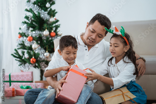 dad and kids with present in christmas day photo