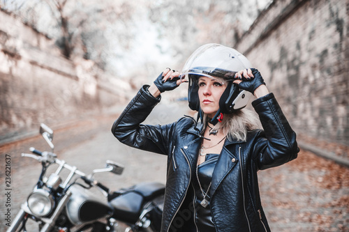 Beautiful biker woman posing outdoor with motorcycle.
