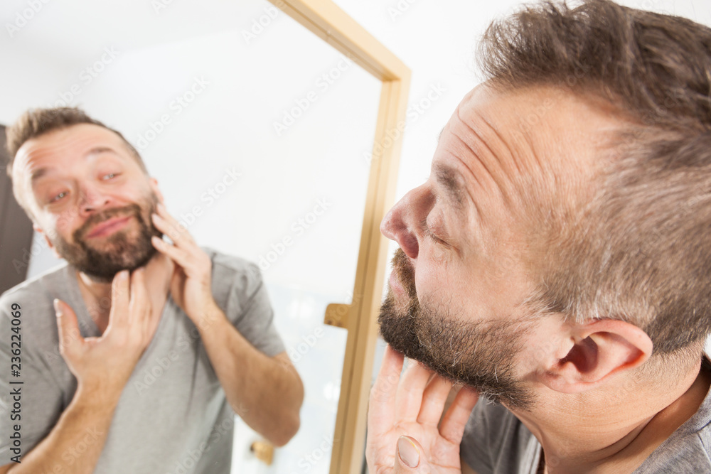 Fototapeta premium Man looking at beard in mirror